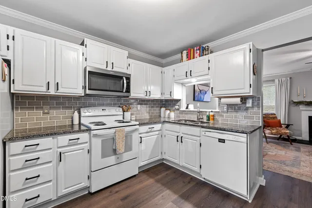 a kitchen with granite countertop white cabinets and white appliances