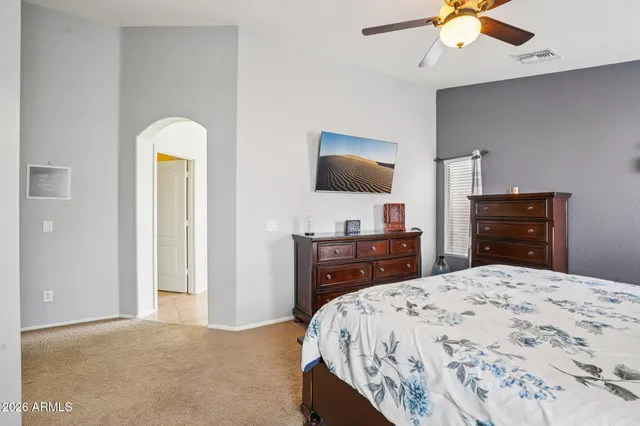 a bedroom with a bed a dresser and a ceiling fan