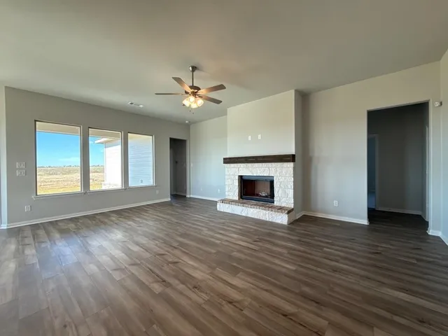 an empty room with wooden floor fireplace and windows