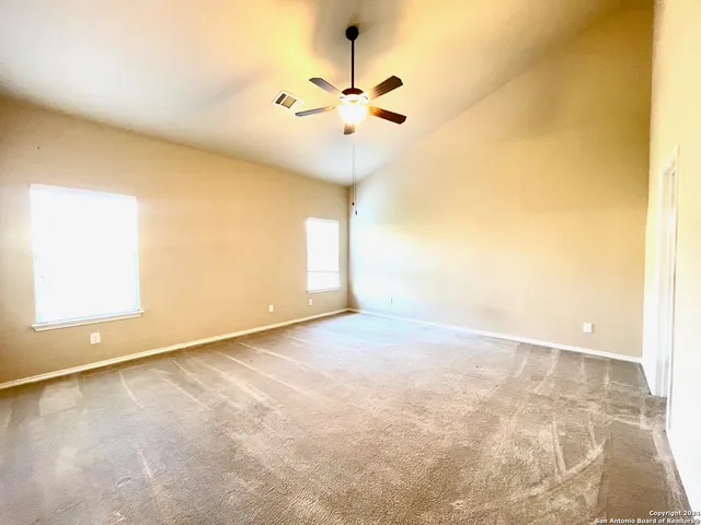 an empty room with a ceiling fan and window