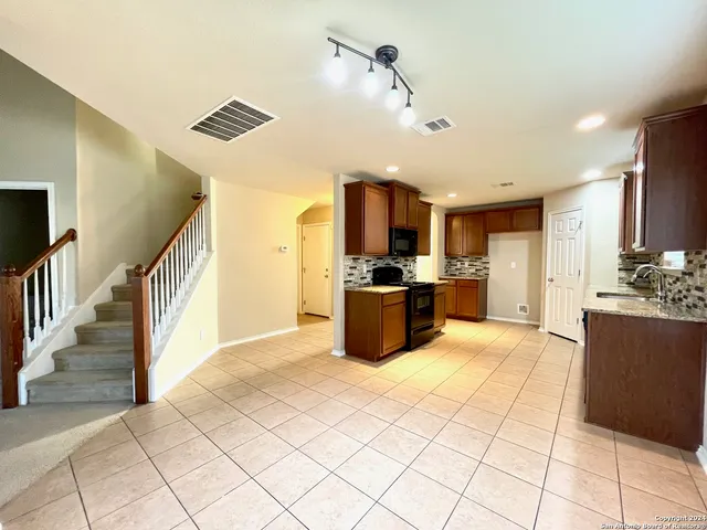 a large kitchen with stainless steel appliances kitchen island granite countertop a refrigerator and a stove top oven