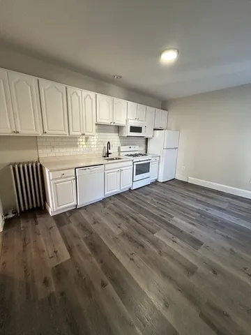 a large kitchen with cabinets appliances a sink and a window