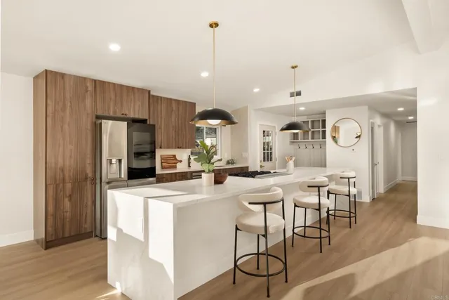 a kitchen with stainless steel appliances granite countertop a table chairs and a refrigerator
