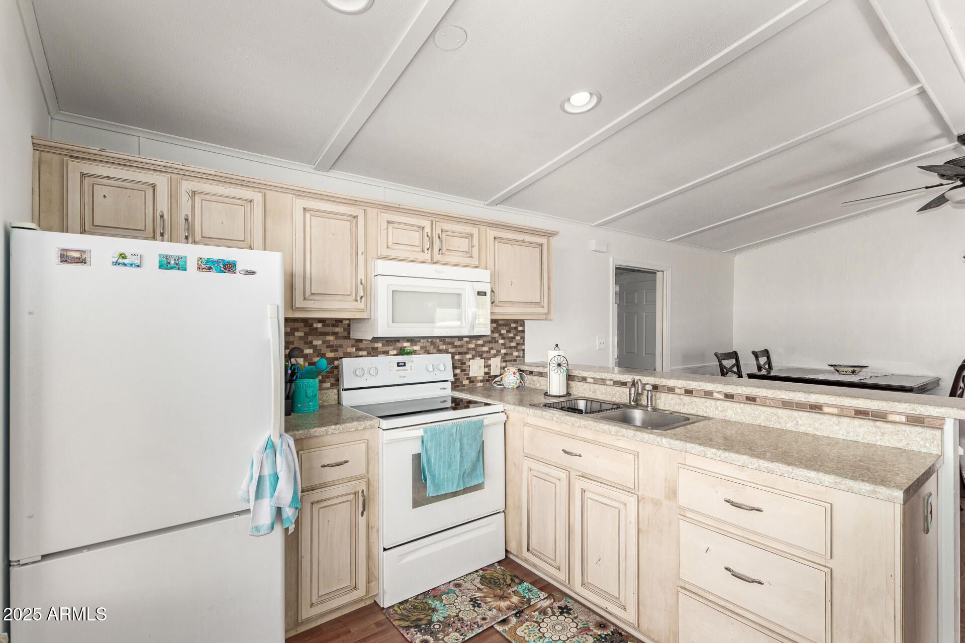 5735 East McDowell Road, Unit 213 Mesa, AZ 85215 - Photo 8 of 18 a kitchen with refrigerator a stove a sink and white cabinets with wooden floor