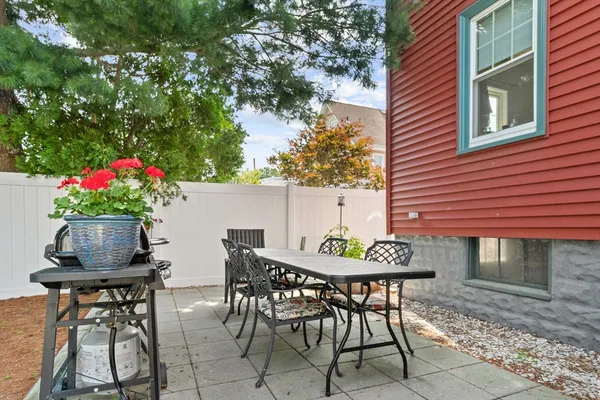 a patio with table and chairs and potted plants