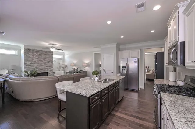 a kitchen with granite countertop center island wooden floor and stainless steel appliances