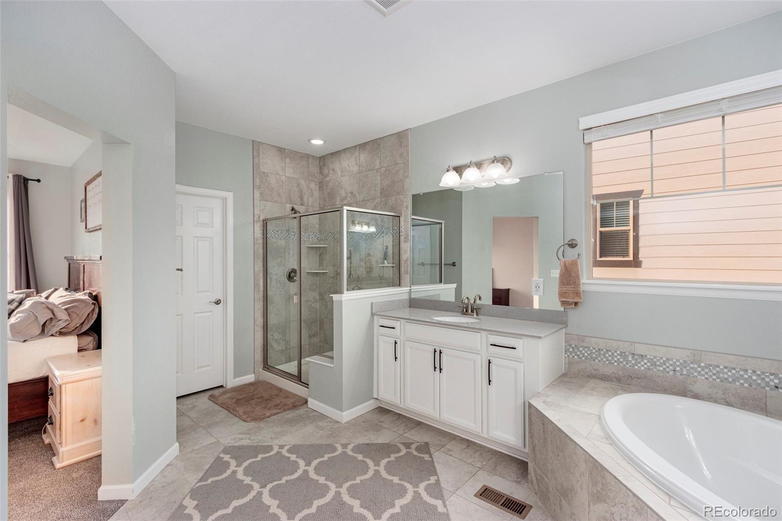 8875 Flattop Way Arvada, CO 80007 - Photo 21 of 38 a spacious bathroom with a granite countertop sink a toilet and shower
