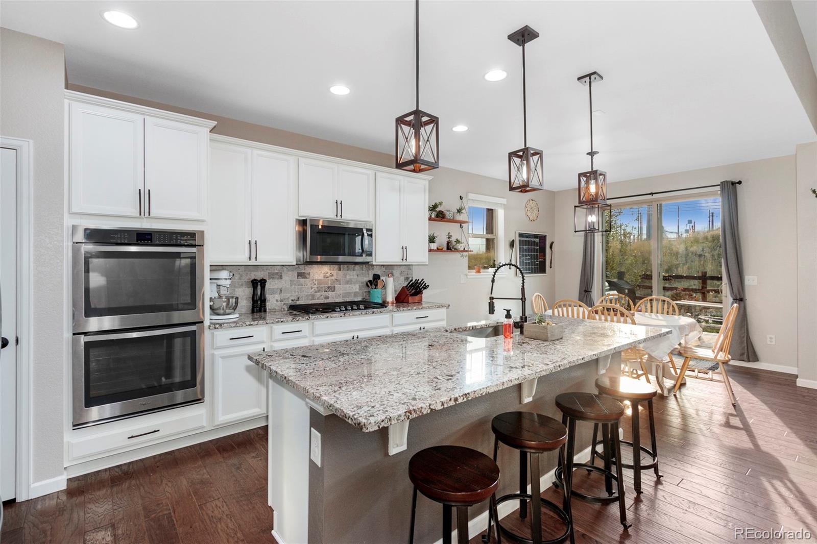 8875 Flattop Way Arvada, CO 80007 - Photo 5 of 38 a kitchen with kitchen island granite countertop a sink a counter space appliances and cabinets