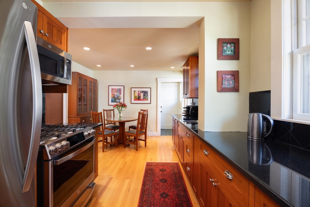 139 University Road, Unit 2 Brookline, MA 02445 - Photo 8 of 16 a kitchen with stainless steel appliances granite countertop a stove top oven a sink a dining table and chairs with wooden floor