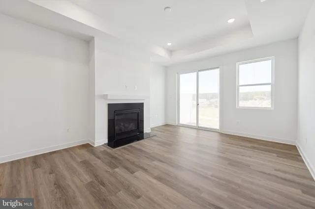 an empty room with wooden floor fireplace and windows