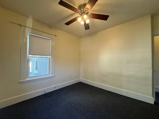 an empty room with a window and a fan