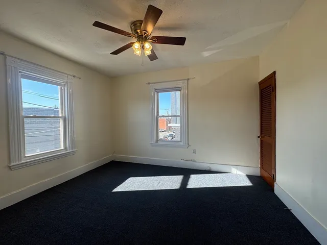 an empty room with a window and a ceiling fan