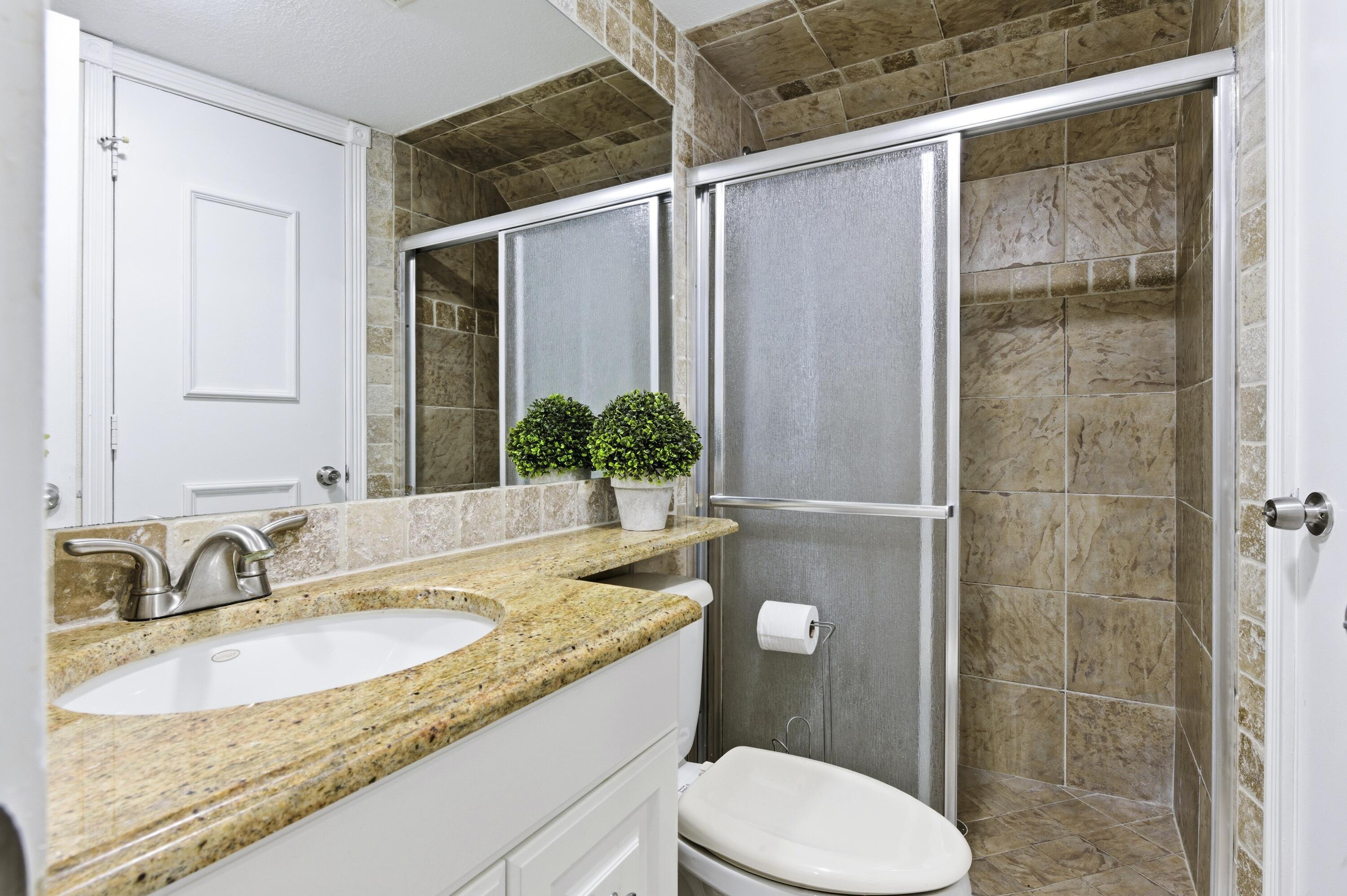 1945 Northwest 4th Avenue, Unit 43C Boca Raton, FL 33432 - Photo 11 of 23 a bathroom with a granite countertop sink toilet and shower