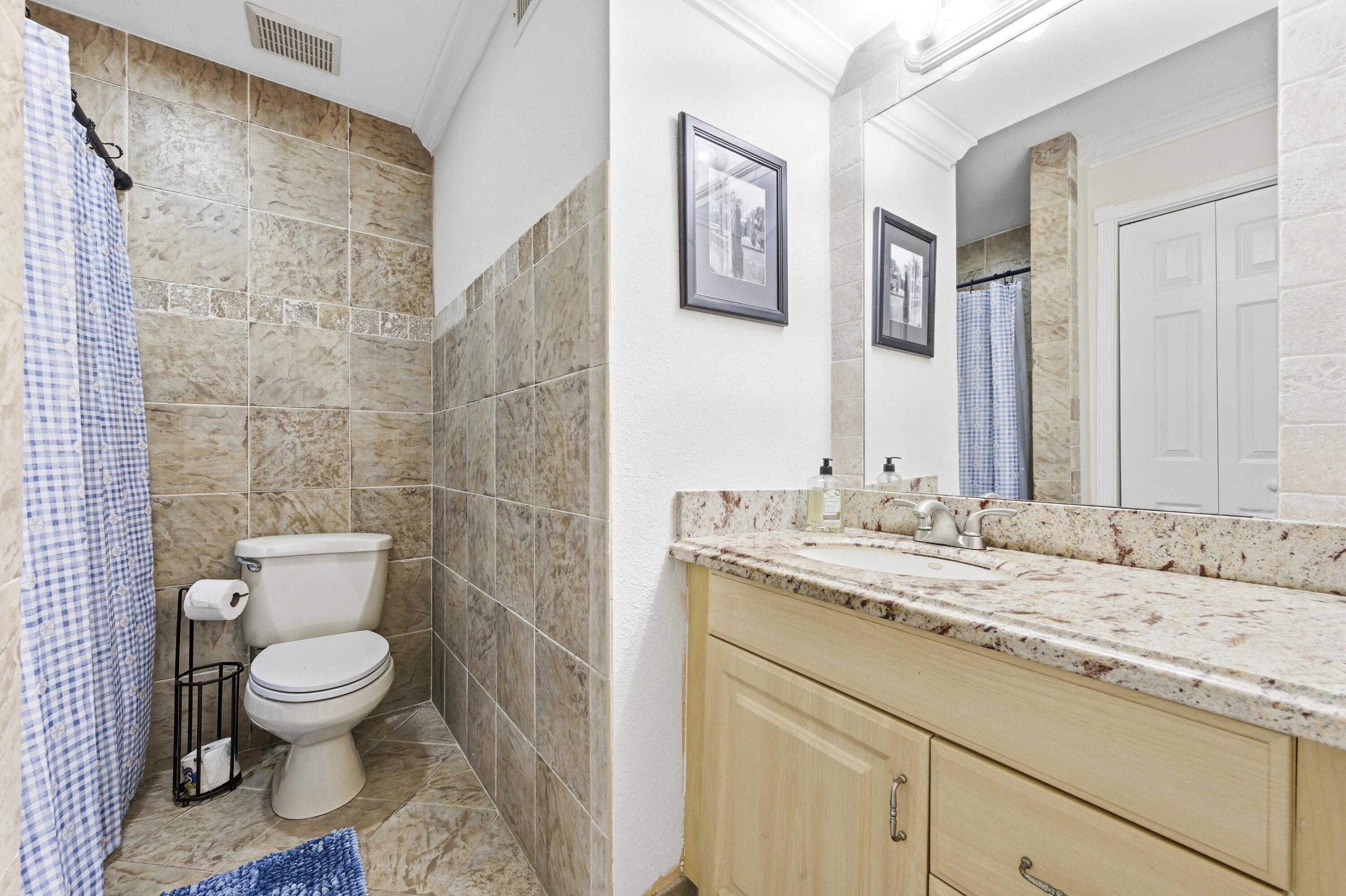 1945 Northwest 4th Avenue, Unit 43C Boca Raton, FL 33432 - Photo 18 of 23 a bathroom with a granite countertop toilet sink and mirror