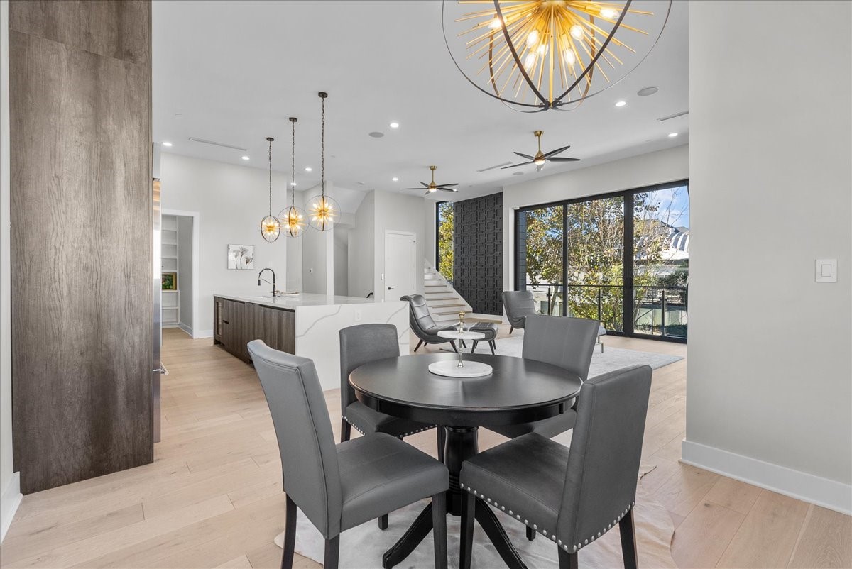 516 Reinerman Street Houston, TX 77007 - Photo 15 of 42 This modern open-concept living space features a sleek kitchen with an island, stylish pendant lighting, and a cozy dining area. Large windows and sliding doors lead to a balcony, allowing for abundant natural light and outdoor views.