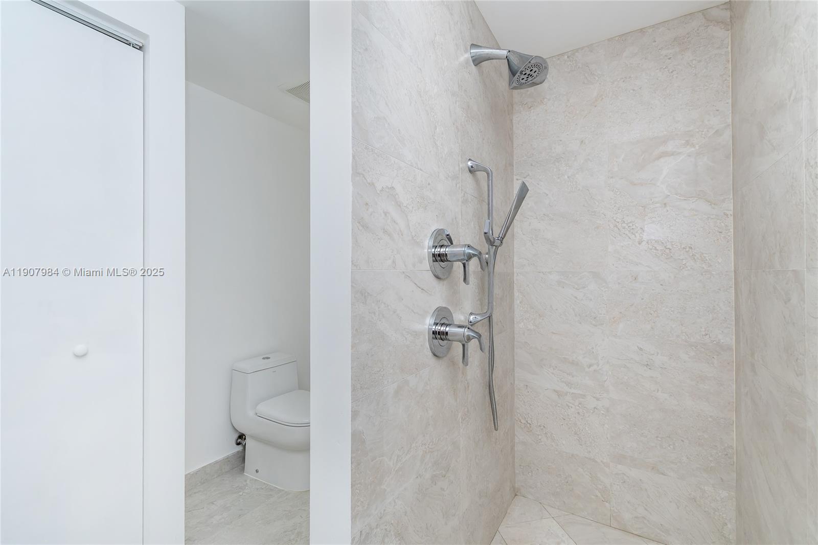 488 Northeast 18th Street, Unit 2810 Miami, FL 33132 - Photo 21 of 31 a bathroom with a granite countertop toilet and a shower