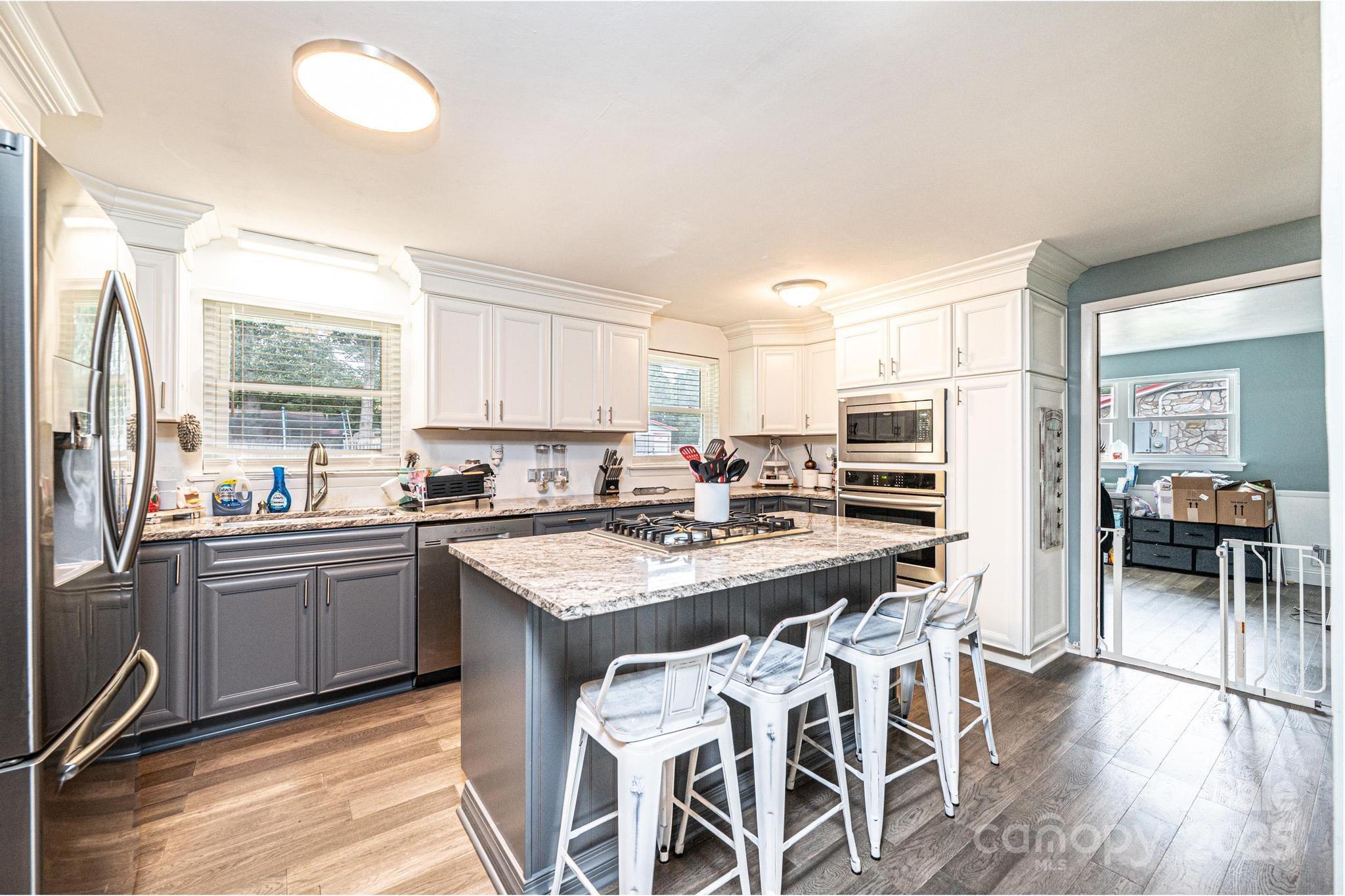 2841 21st Street Northeast Hickory, NC 28601 - Photo 6 of 43 a kitchen with stainless steel appliances granite countertop a stove top oven a sink dishwasher and a dining table with wooden floor
