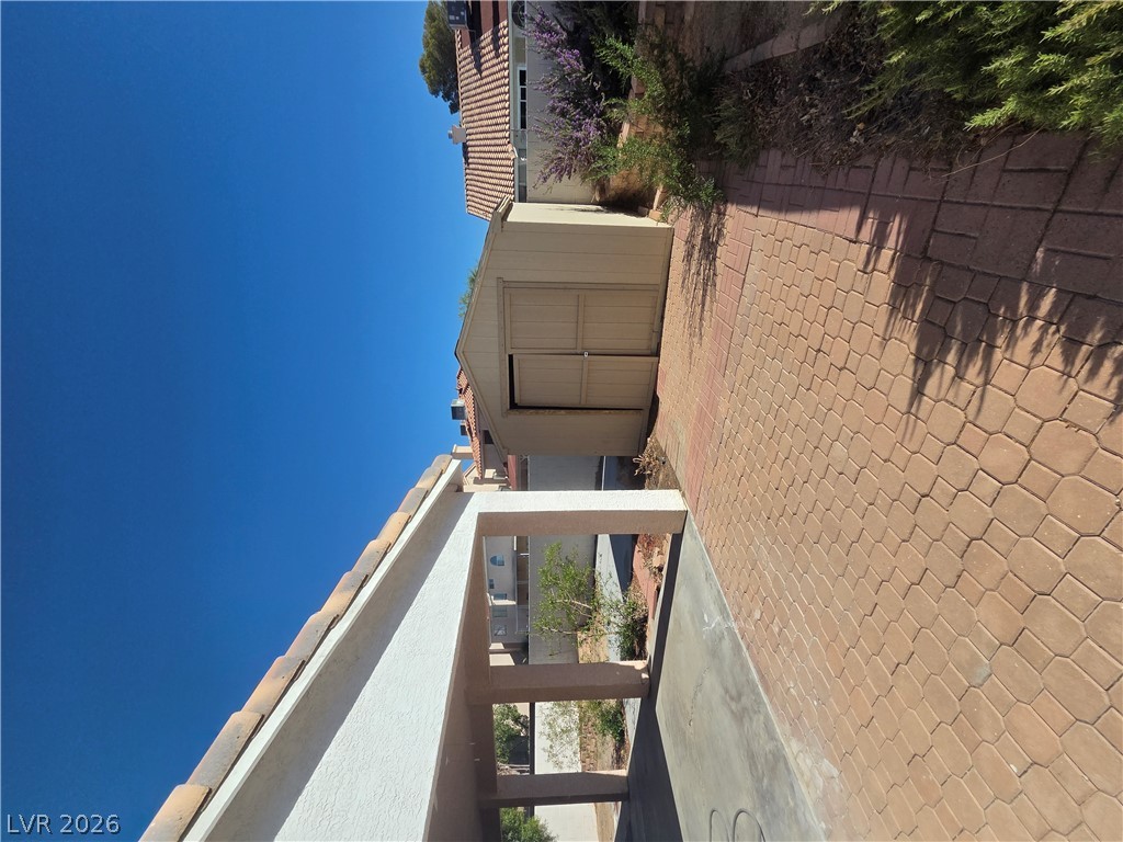 1429 Hawkwood Road Henderson, NV 89014 - Photo 51 of 53 A paved side yard features a detached storage shed set against desert landscaping.