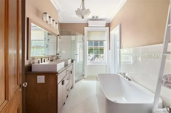 a spacious bathroom with a double vanity sink a mirror a bathtub and next to a window