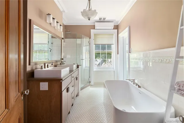 a spacious bathroom with a double vanity sink a mirror a bathtub and next to a window