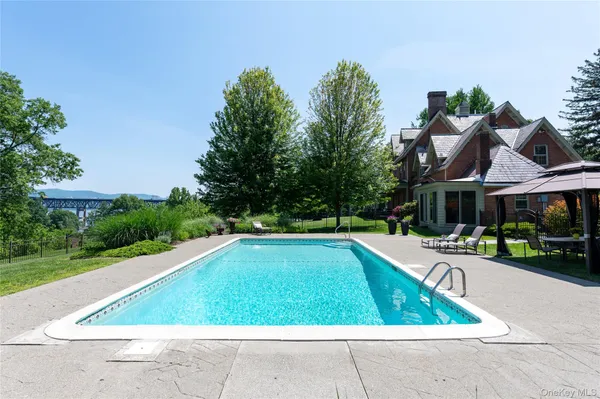 a view of swimming pool with lawn chairs and plants