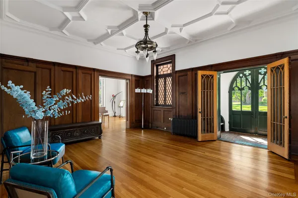 a living room with furniture potted plant floor to ceiling window and a flat screen tv