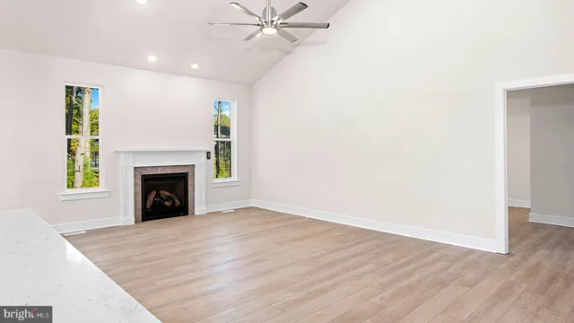 a view of an empty room with wooden floor fireplace and a window