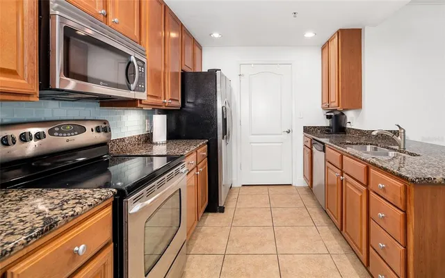 a kitchen with stainless steel appliances granite countertop a stove a sink and a microwave
