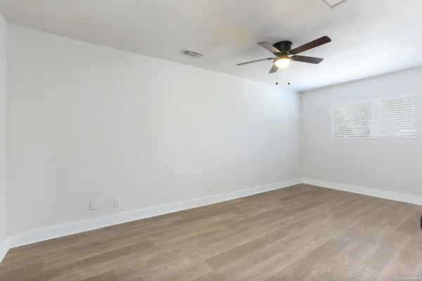 a view of empty room with wooden floor and fan