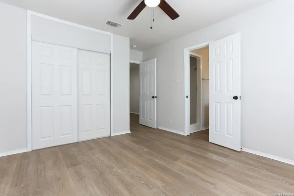 an empty room with ceiling fan and window