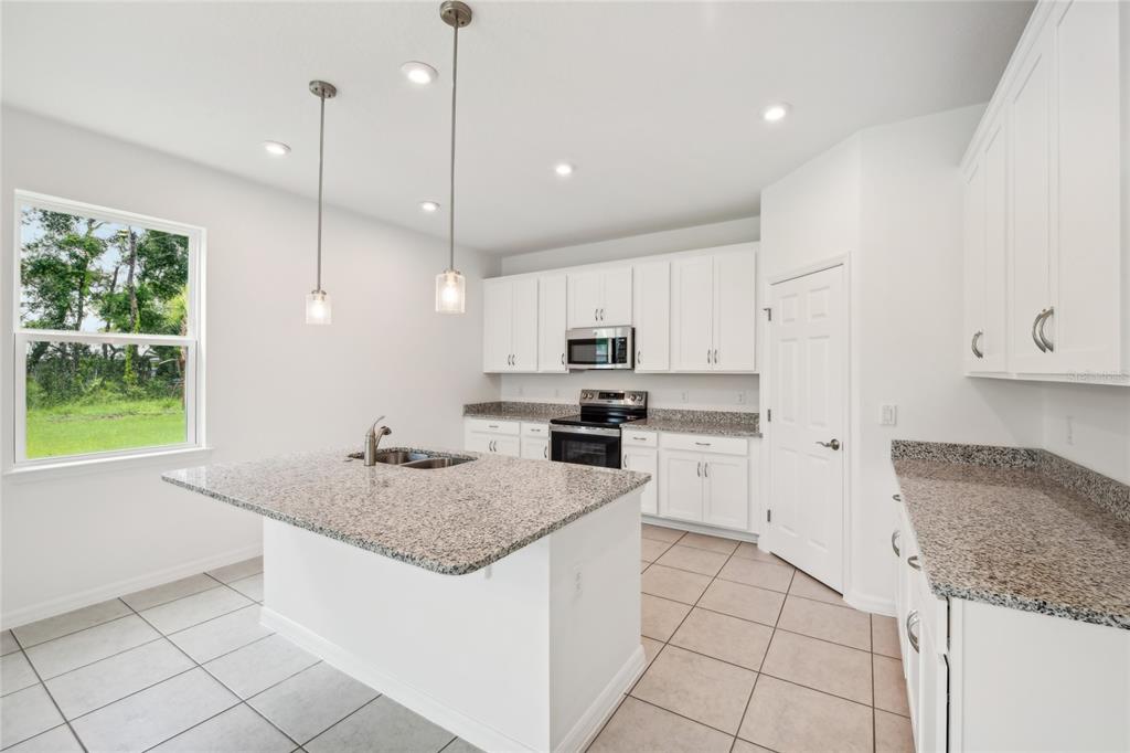 9596 Starling Loop Leesburg, FL 34788 - Photo 13 of 39 a kitchen with stainless steel appliances granite countertop a sink a oven and a refrigerator