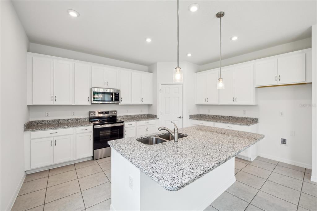 9596 Starling Loop Leesburg, FL 34788 - Photo 14 of 39 a kitchen with granite countertop a sink a counter top space appliances and cabinets