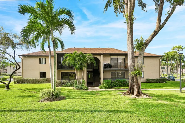 a front view of a house with a yard and palm trees