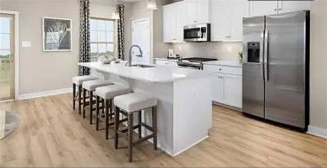 a kitchen with stainless steel appliances kitchen island granite countertop a refrigerator a stove a microwave oven a sink with island and chairs
