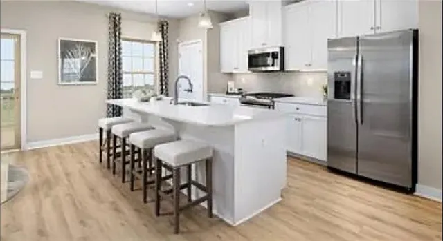 a kitchen with stainless steel appliances a refrigerator a sink a stove a dining table and chairs