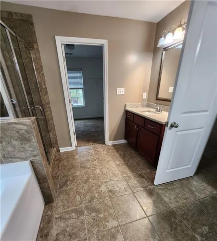 a view of an empty room with wooden floor and a kitchen
