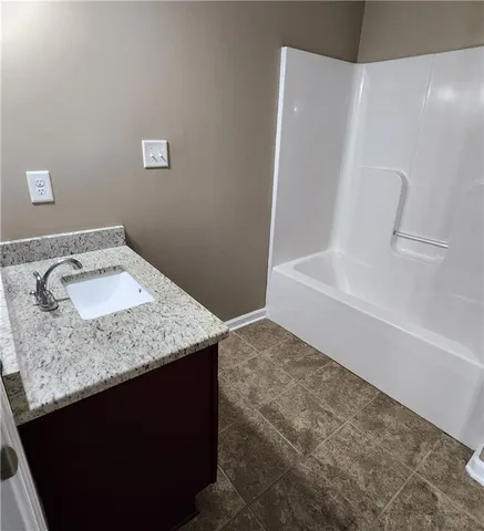 a bathroom with a granite countertop sink and a bathtub