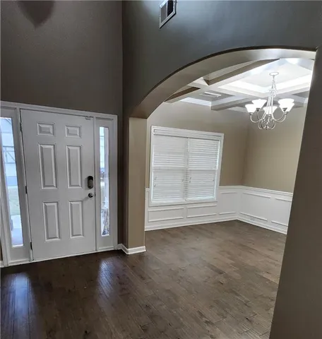 an empty room with wooden floor cabinet and windows