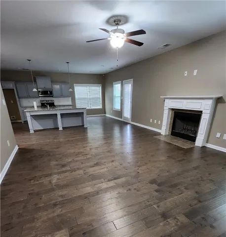 a view of an empty room with kitchen view and a fireplace
