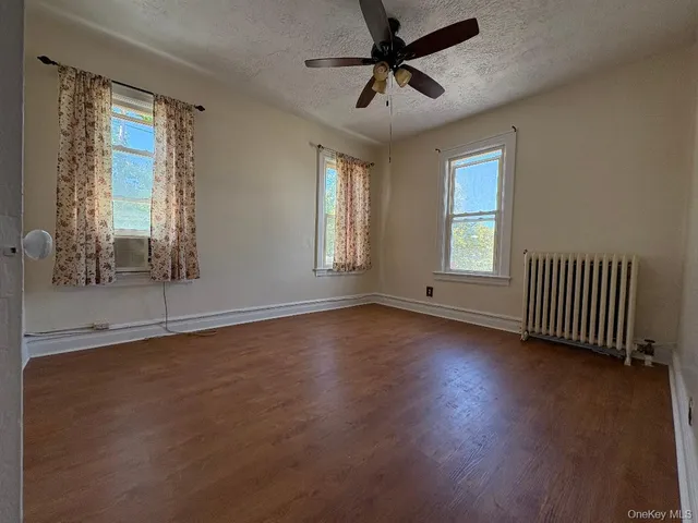 a view of an empty room with a window and wooden floor