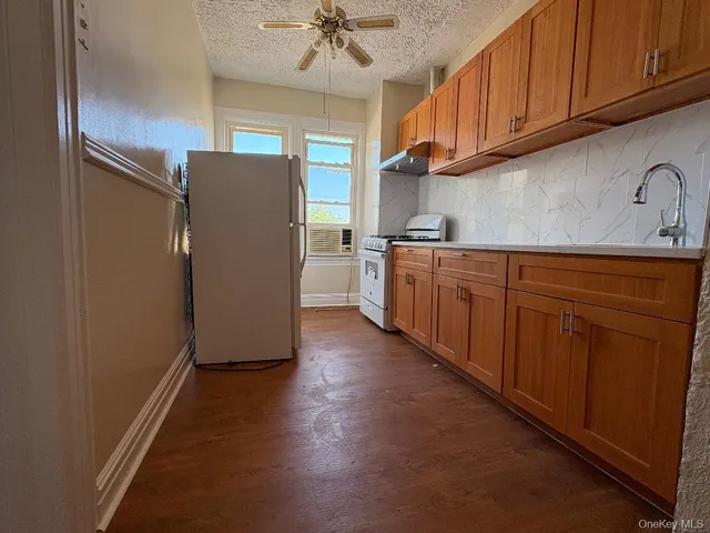 a kitchen with stainless steel appliances granite countertop a refrigerator a sink dishwasher and wooden cabinets with wooden floor