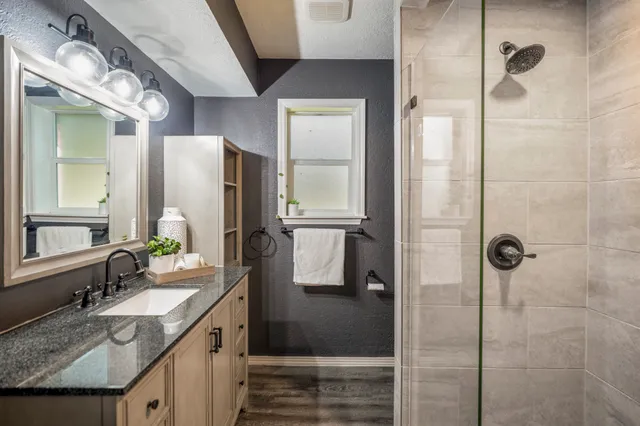 a bathroom with a granite countertop shower a sink and mirror