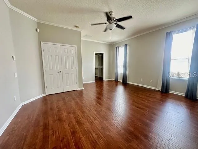 an empty room with wooden floor and ceiling fan
