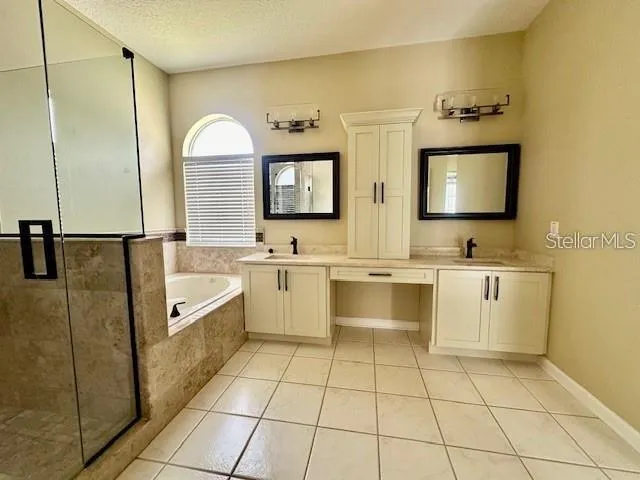 a spacious bathroom with a double vanity sink mirror and bathtub