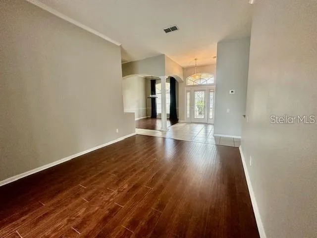 a view of an empty room with wooden floor and a window