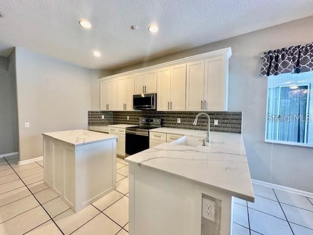806 Winder Oaks Drive Gotha, FL 34734 - Photo 4 of 47 a kitchen with kitchen island granite countertop a stove top oven a sink a counter top space and cabinets