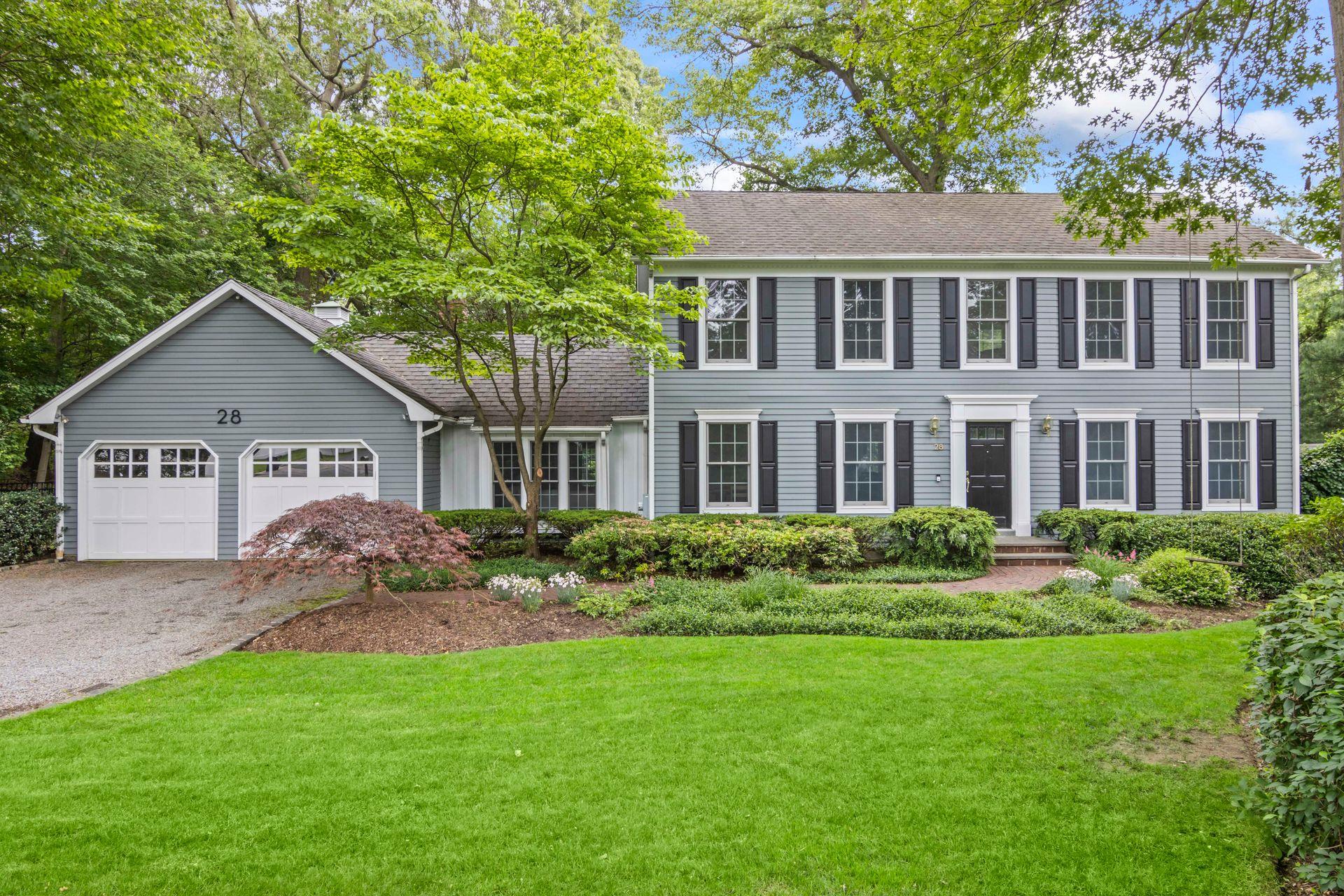 Colonial inspired home featuring a garage, asphalt driveway, a front lawn, and a shingled roof