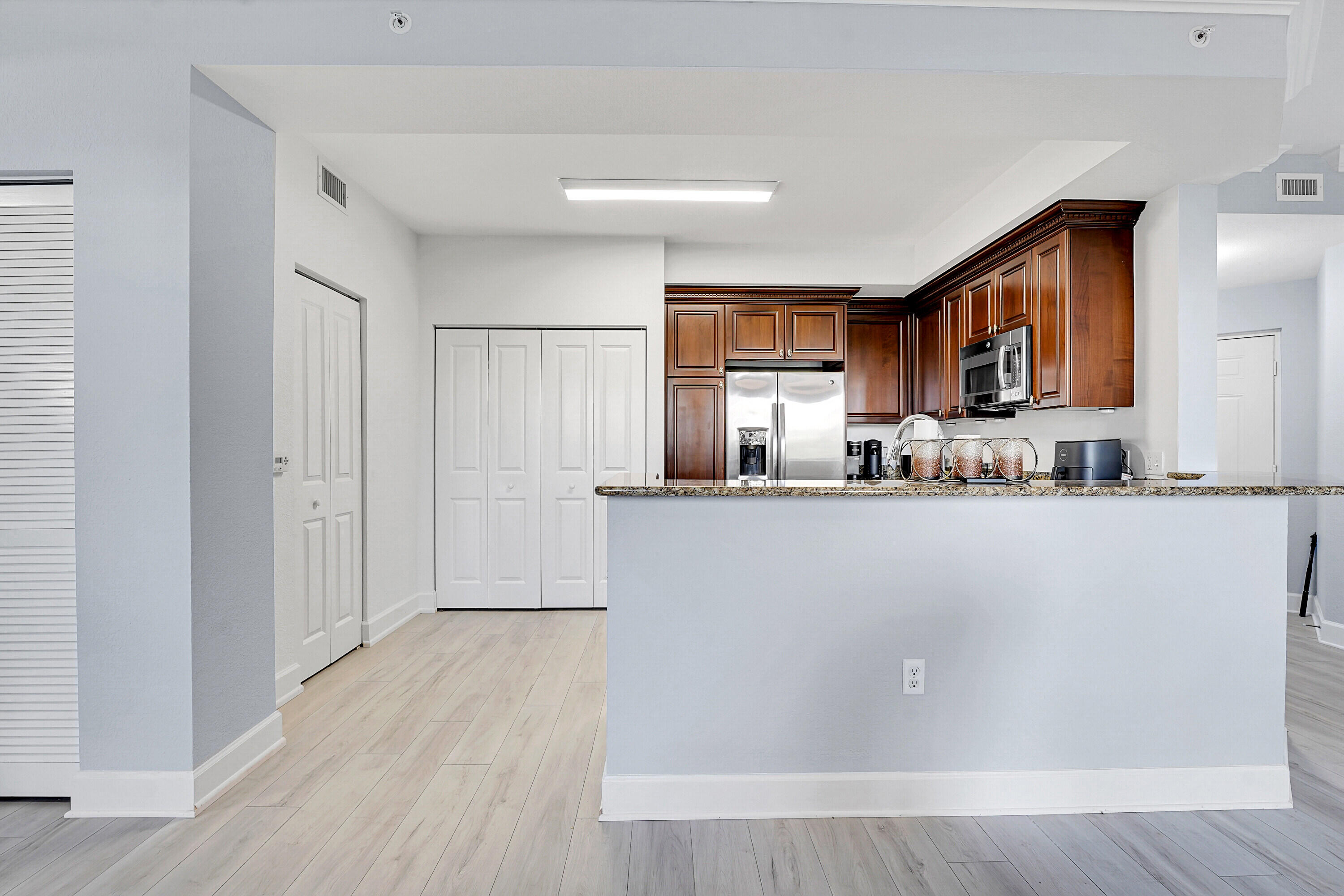 1690 Renaissance Commons Boulevard, Unit 1401 Boynton Beach, FL 33426 - Photo 4 of 43 a living room with stainless steel appliances granite countertop a refrigerator a sink a stove a microwave and cabinets