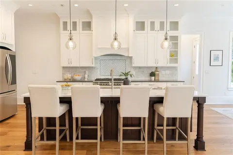 a white kitchen with a dining table chairs and white cabinets
