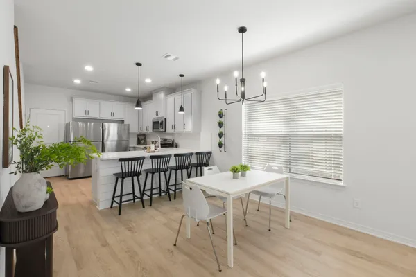 a view of a dining room and livingroom with furniture wooden floor a chandelier